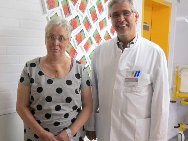 Ein Mann in weißem Kittel und eine Frau stehen in einem Krankenhausflur