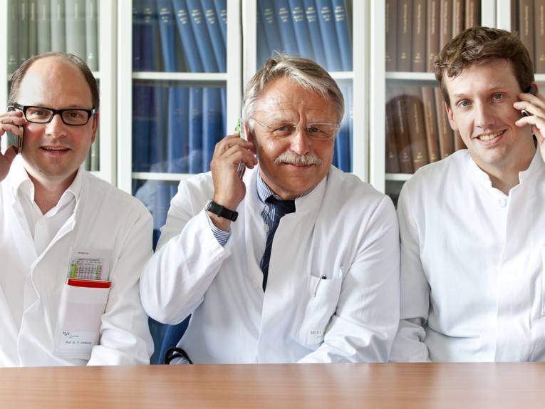 Drei Männer mit Telefonen am Ohr