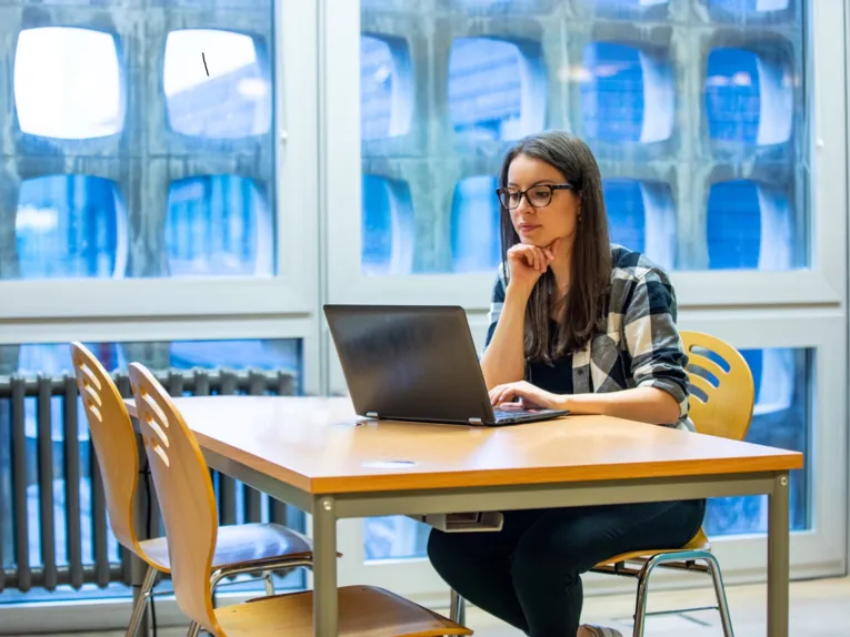 Frau an einem Tisch sitzend mit Notebook