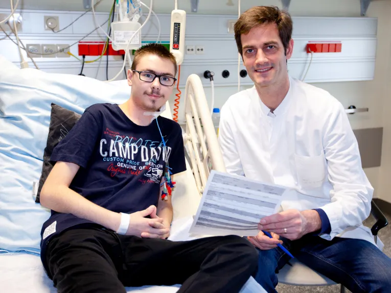 Zwei Männer sitzen auf einem Krankenhausbett.