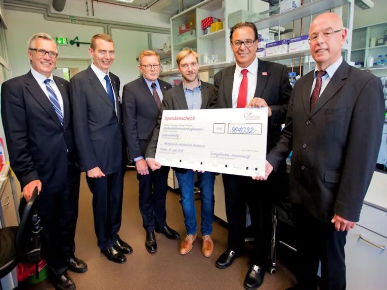 Sechs Männer mit einem symbolischen Spendenscheck.