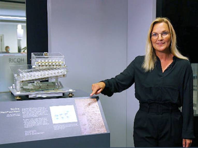 Frau zeigt auf ein Exponat in einer Ausstellung