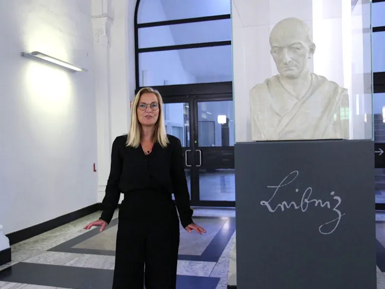 Frau neben einer Büste hinter Glas