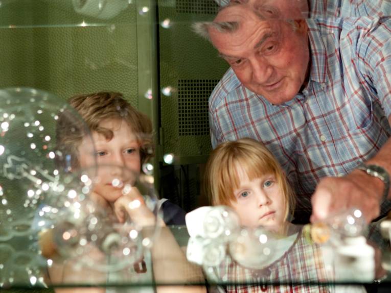 EIn Mann und zwei Kinder schauen sich Glühbirnen an.