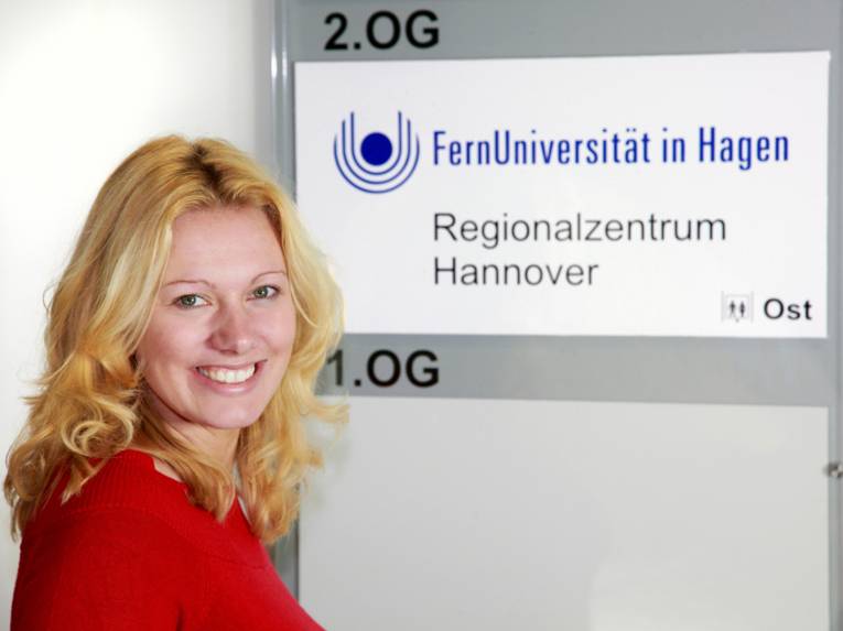 blonde Studentin vor Uni-Wegweiser