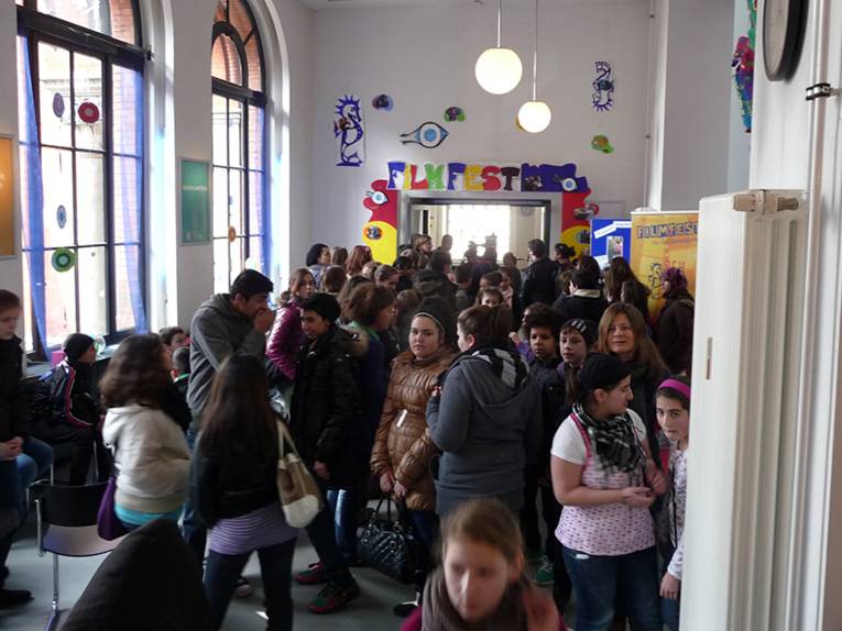 Ein Kino-Foyer mit vielen Kindern und Erwachsenen. 