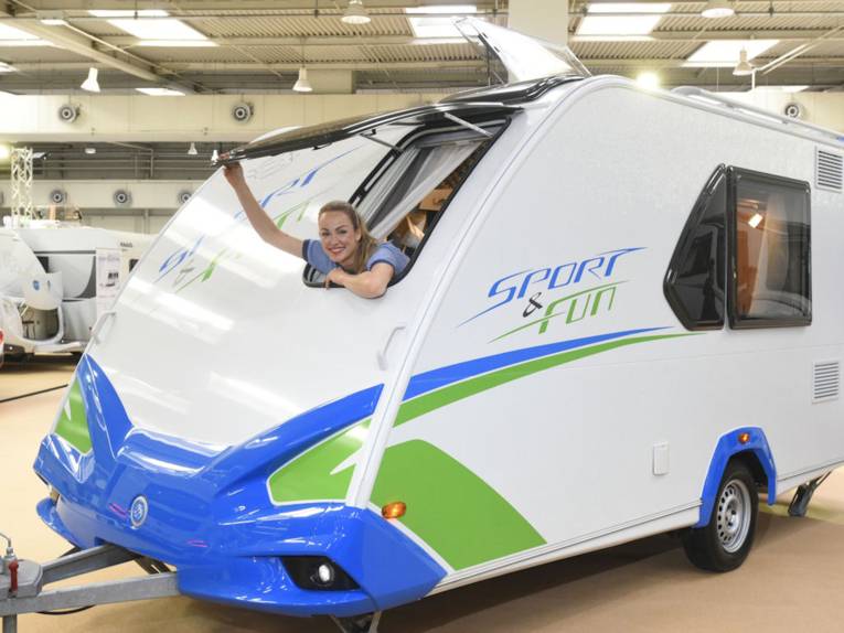 Frau lehnt sich aus Fenster eines Wohnwagens.