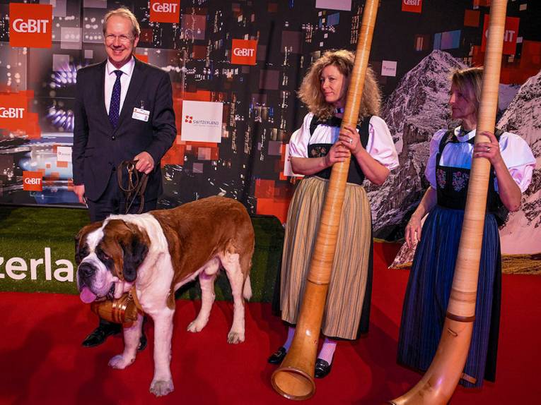 Mann mir Hund und zwei Frauen in Trachten mit Alphörnern