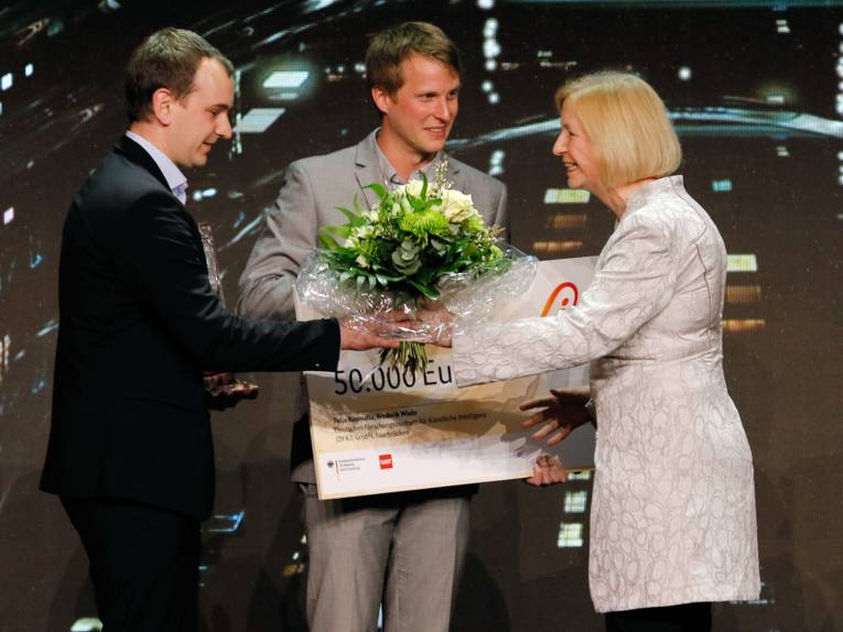 Eine Frau und zwei Männer mit Blumenstrauß