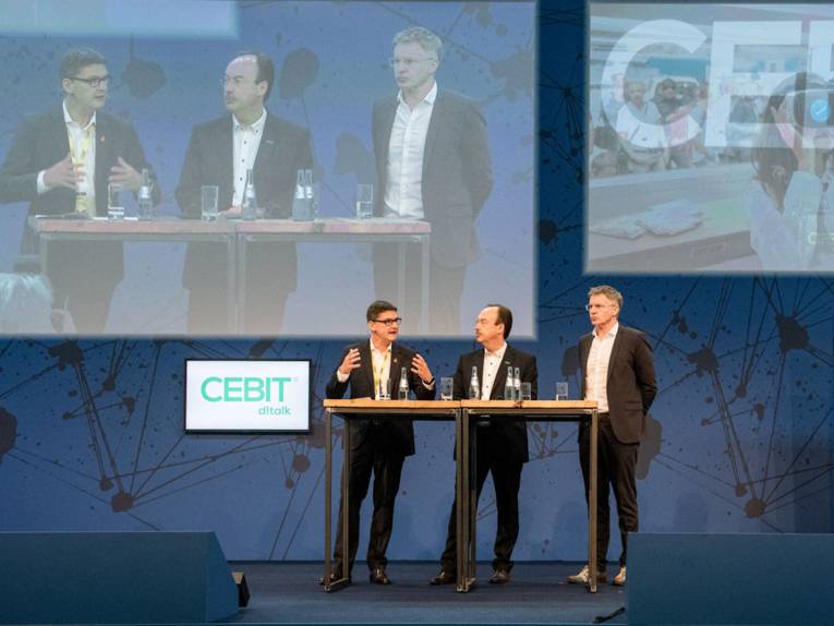 Drei Männer an einem Stehtisch.