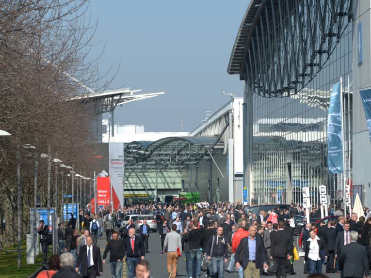 Viele Menschen auf dem Messegelände zwischen großen Hallen.