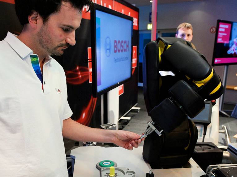 Mensch mit Arm eines Industrieroboters