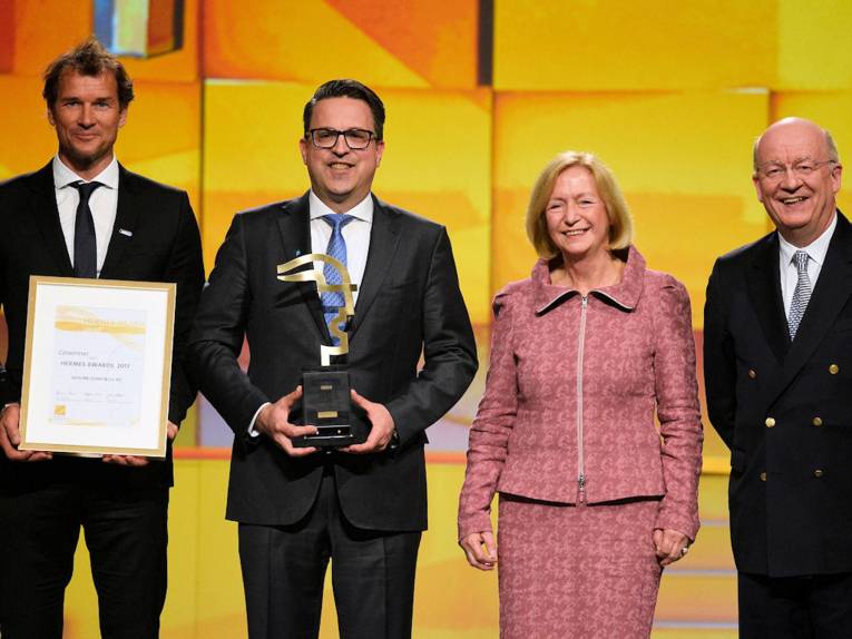 Eine Frau und drei Männer mit Urkunde und Auszeichnung.