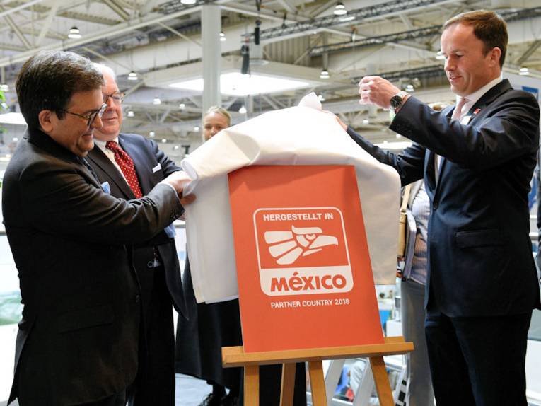 Zwei Männer enthüllen eine Tafel mit der Aufschrift "Mexiko"