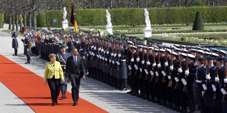 Mann und Frau schreiten auf einem roten Teppich vor einem Soldatenspalier