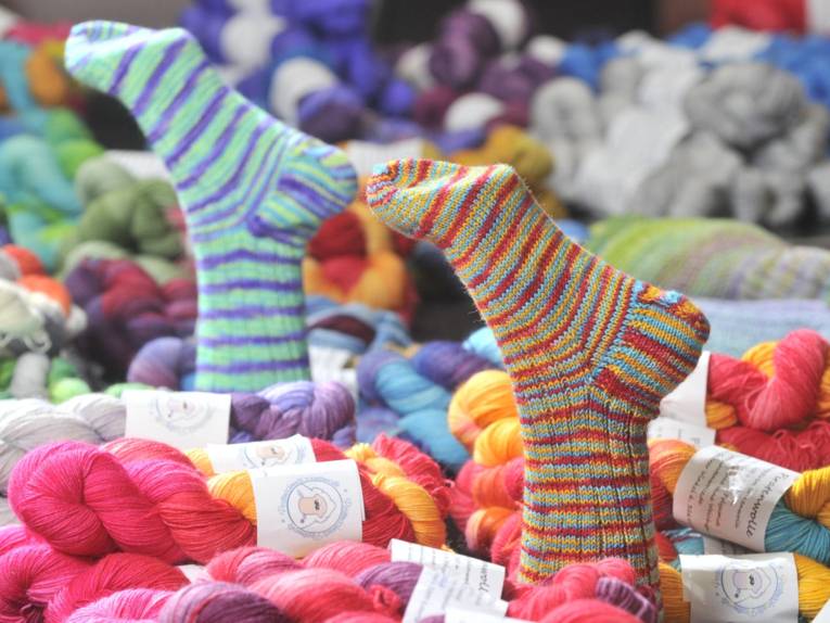 Jede Menge Wolle und zwei Füße, die ihre Wollsocken in die Luft halten.