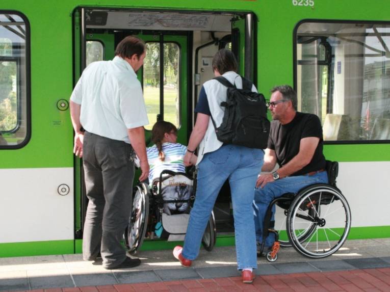 Rollstuhlfahrer erhalten Unterstützung beim Einstieg in eine Stadtbahn.