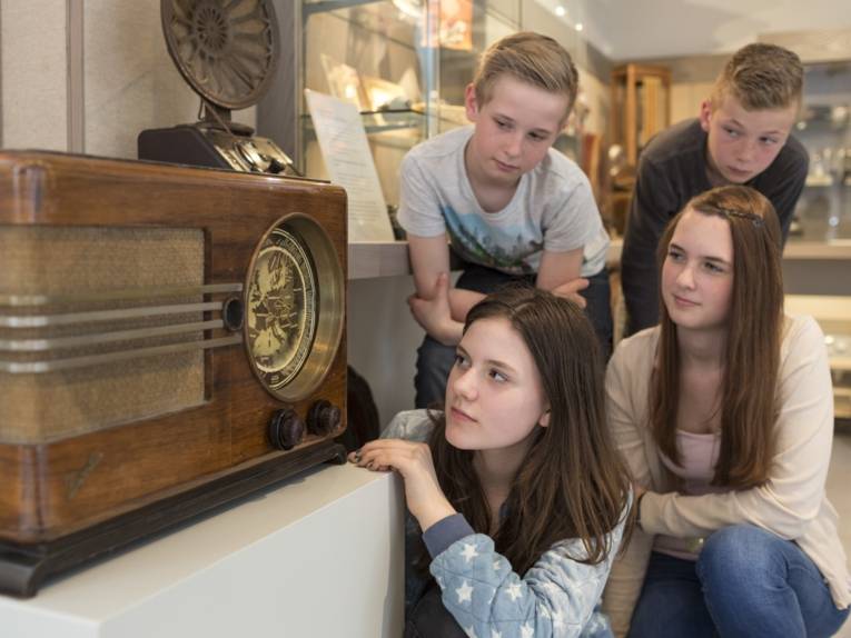 Zwei Mädchen und zwei Jungen vor einem alten Radioapparat
