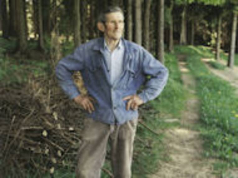 Portrait alter Mann in Arbeitskleidung vor einem Waldstück