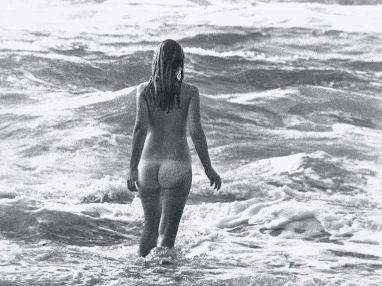 Nackte Frau am Strand mit Wellen