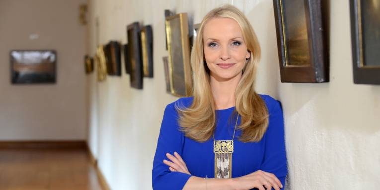 Frau vor einer Wand mit Gemälden.