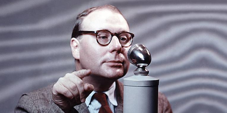 Foto eines Mannes mit Brille vor einem Radiomikrofon.