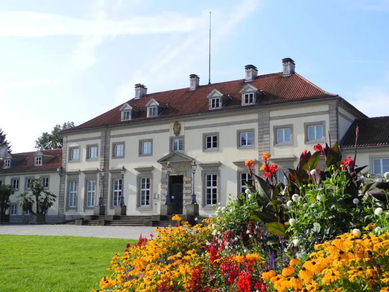 Haus mit Wiese und blühendem Blumenbeet davor.