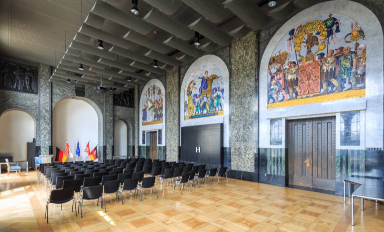 Bestuhlter Saal mit Mosaiken an den Wänden