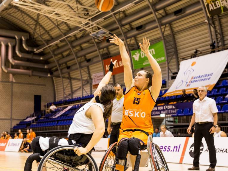 Zwei Frauen in Rollstühlen spielen Basketball