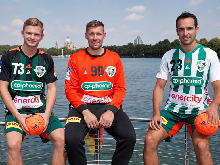 Drei Handballspieler sitzen an einem See