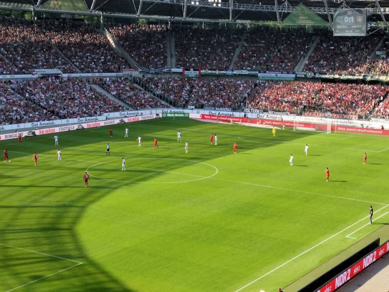 Blick in gefülltes Stadion mit Fußballspielern auf dem Feld