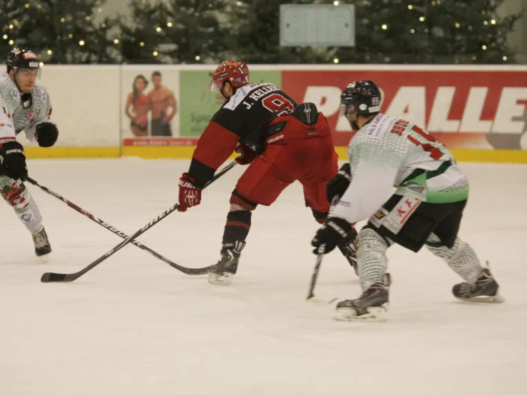 Drei Eishockeyspieler kämpfen um den Puck.