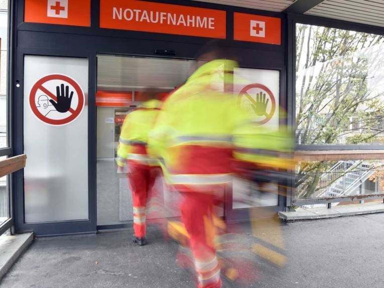 Zwei Sanit&auml;ter an einem Klinikeingang mit Schild Notaufnahme