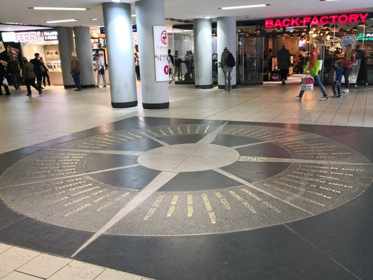 In den Boden eingelassener Kompass mit Entfernungsangaben