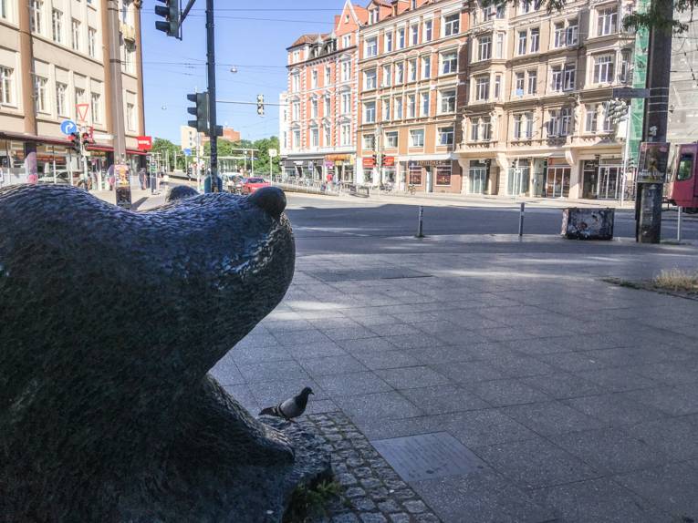 Blick in einen Straßenzug, vorn links steht eine Bärenplastik