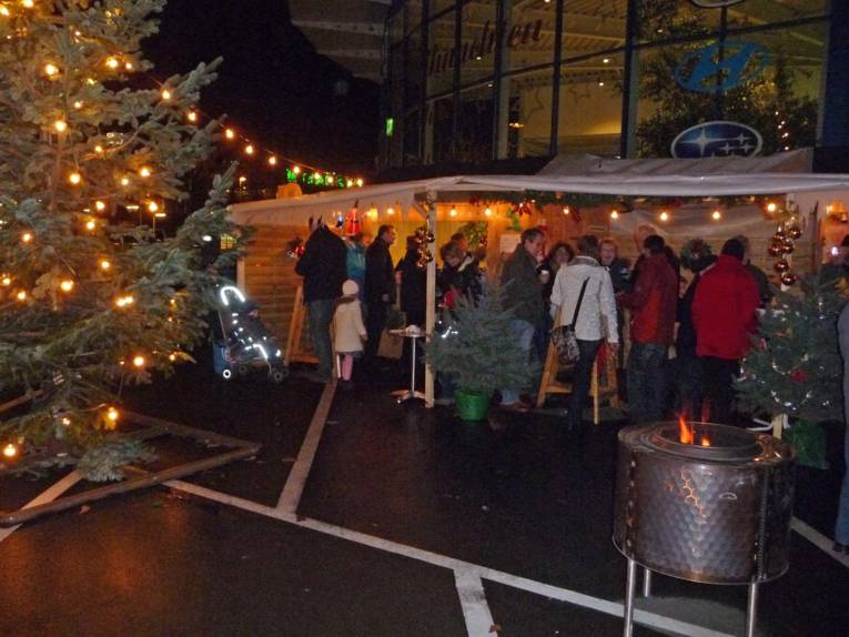 Verkaufsbuden, geschmückte Tannenbäume und Besucher.