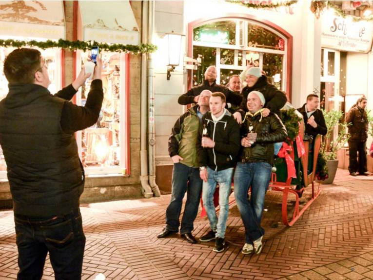 Ein Gruppe wird vor einem großen Pferdeschlitten fotografiert