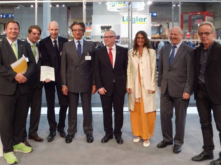 Mehrere Männer und eine Frau in festlicher Kleidung stehen nebeneinander