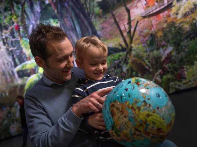 Mann zeigt einem Kind etwas auf einem Globus
