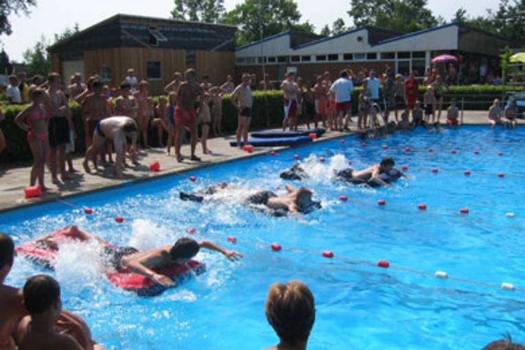 Jugendliche auf Luftmatratzen beim Wettkampf im Schwimmbad