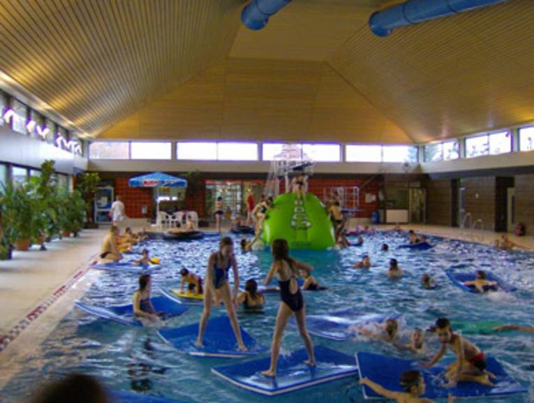Viele Kinder toben mit Badematten im Schwimmbecken