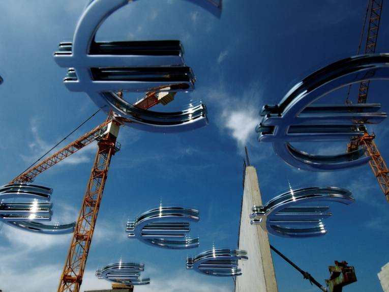 Man sieht zwei Kräne und viele Eurozeichen über das Bild verteilt