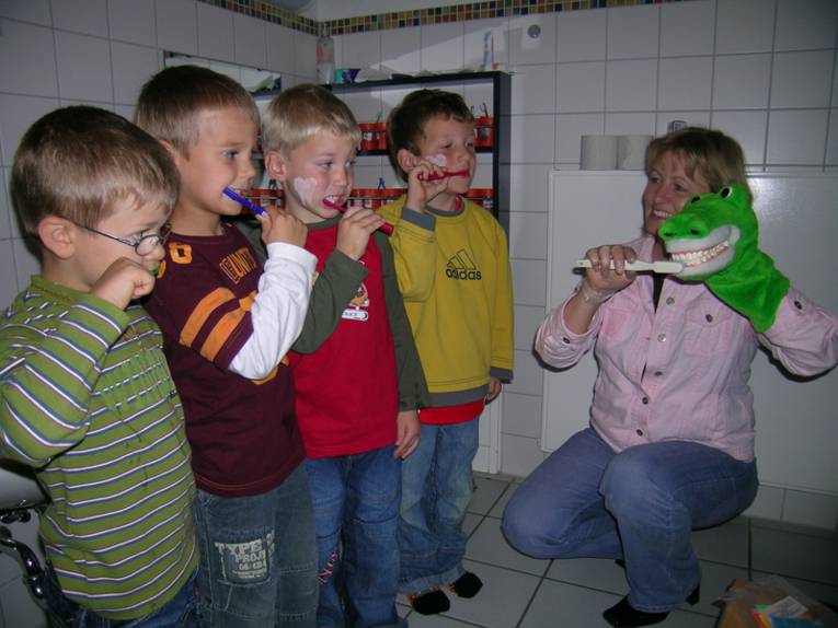 Kinder putzen unter Anleitung des Zahnkrokodils Zähne