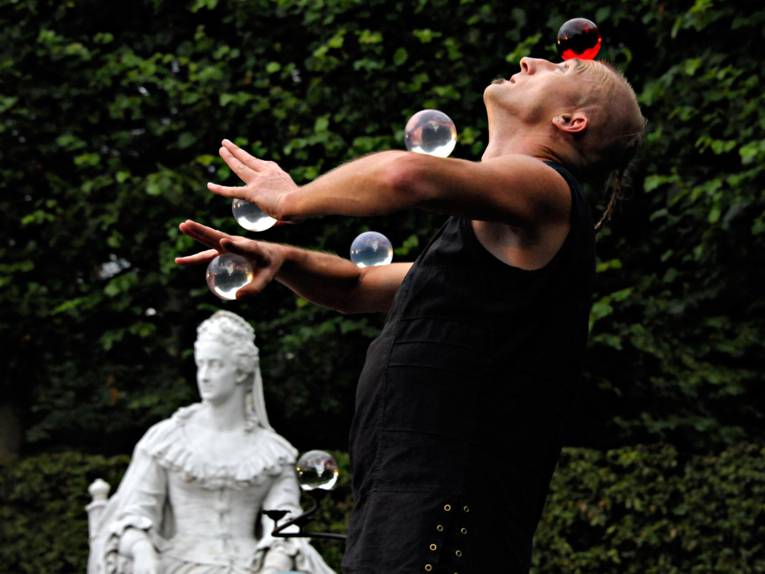 Ein Mann jongliert durchsichtige Glaskugeln auf seinem Körper