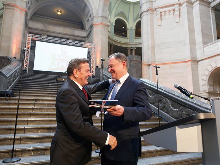 Gerhard Schröder und Stephan Weil umarmen sich auf der Treppe in der Rathaushalle