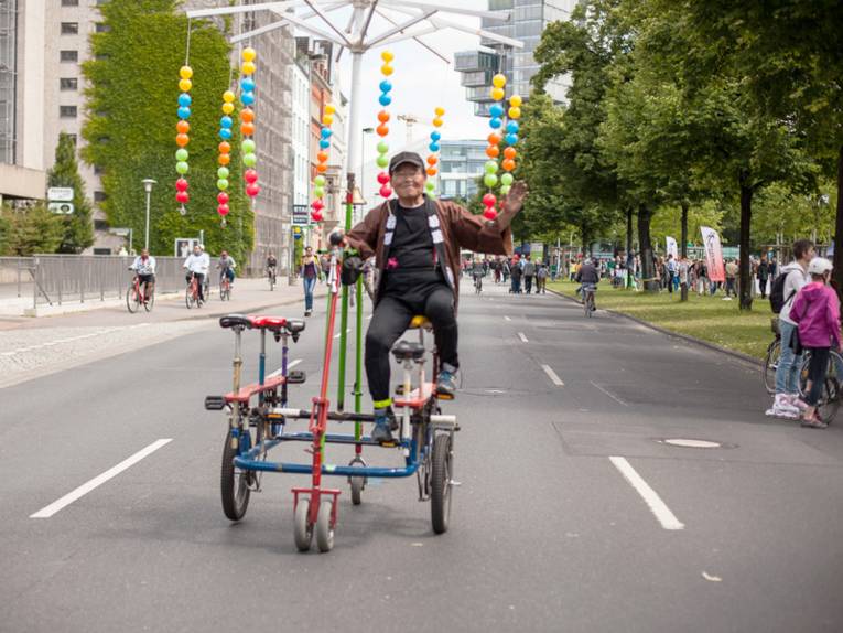 Ein Mann fährt mit einem bunten Mehrpersonenfahrrad auf dem Friedrichswall