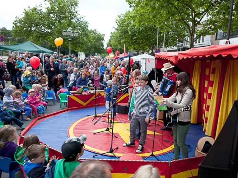 Kinder singen vor anderen Kindern und Eltern in einem Rondell auf der Georgstraße