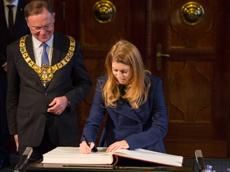 Oberbürgermeister Weil beobachtet Prinzessin Beatrice, während sie sich ins Goldene Buch der Stadt einträgt