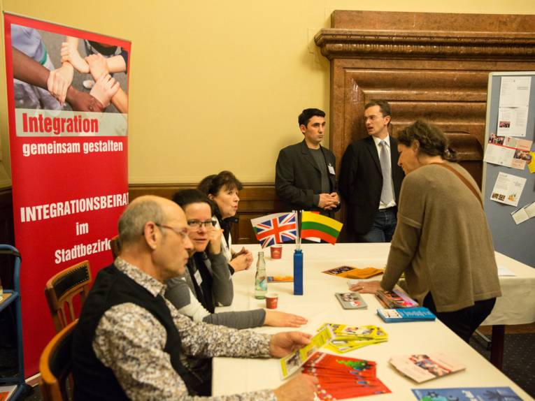 Ein Dutzend Personen an einem Tisch, auf dem Info-Materialien liegen