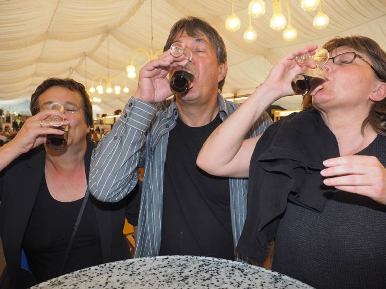 Drei Menschen, die Lüttje Lage trinken. 